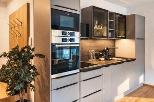 a kitchen with white cabinets and a stove at RUHESTUBE - Design Apartment with Balcony in Fügen