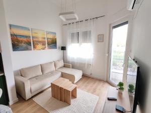 a white living room with a couch and a table at Apartman Petkov in Palić
