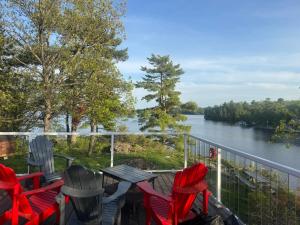 Eine Terrasse mit Stühlen, einem Tisch und Blick auf einen Fluss in der Unterkunft Pickerel Point in Port Severn