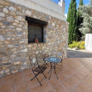 a patio with a table and chairs and a stone wall at Cortijo La Joya in Lanjarón