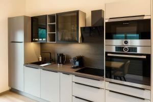 a kitchen with white cabinets and stainless steel appliances at GLETSCHERBLICKSTUBE - Terrace & Mountain View in Fügen