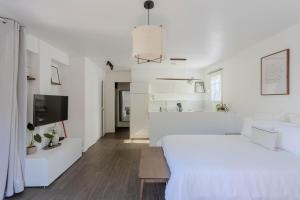 a white bedroom with a large bed and a tv at Studio lumineux avec jardin privé et parking in La Turbie +11 photos
