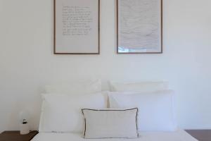 a bed with white pillows and two pictures on the wall at Studio lumineux avec jardin privé et parking in La Turbie