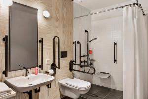 a bathroom with a sink and a toilet and a shower at Moxy Kaunas Center in Kaunas +63 photos