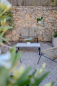 two benches and a table in front of a stone wall at Studio lumineux avec jardin privé et parking in La Turbie