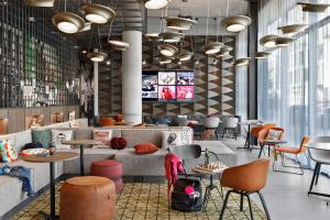 a restaurant with tables and chairs and a couch at Moxy Kaunas Center in Kaunas