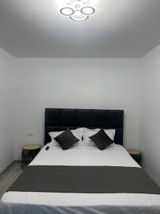 a bedroom with a black and white bed with pillows at Nova Residence Craiova in Craiova