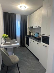 a kitchen with white cabinets and a table and a chair at Nova Residence Craiova in Craiova