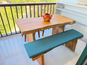 a wooden table with a cup and a bench on a balcony at Marulhos resort Muro Alto flats Premium frente ao mar in Porto De Galinhas