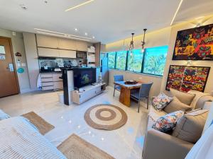 a living room with a couch and a tv and a table at Marulhos resort Muro Alto flats Premium frente ao mar in Porto De Galinhas