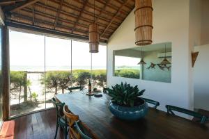 a dining room with a wooden table and a large window at Hotel Manati in Barra Grande
