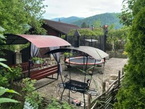 a patio with a table and a bench in a garden at САДИБА та ЧАН "NA PAGORBI" in Yaremche
