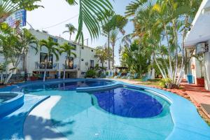 a swimming pool in front of a house with palm trees at Hotel Rivera Del Mar in Puerto Escondido