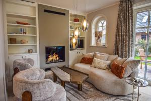 a living room with a couch and chairs and a fireplace at Die Perle von Wenningstedt in Braderup