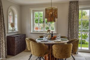 a dining room with a table and chairs and windows at Die Perle von Wenningstedt in Braderup