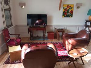 a living room with leather furniture and a television at Château des Boulais Suite in Saint-Martin-le-Bouillant
