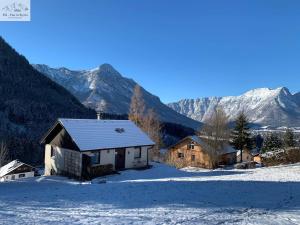 a house in the snow with mountains in the background at Ferienhaus Kleinod in Bad Aussee