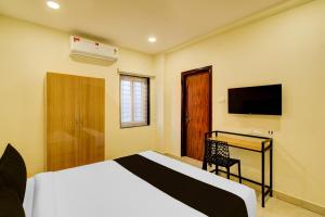 a bedroom with a bed and a desk and a television at Super Hotel O Nivara in Hyderabad