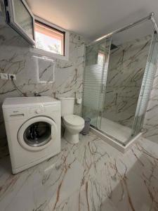 a bathroom with a washing machine and a toilet at ST-Home in Loutsa