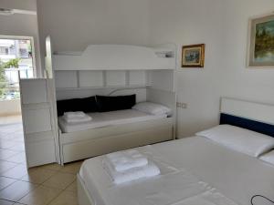 a white bedroom with two beds and a window at Monda Apartments Dhermi in Dhërmi