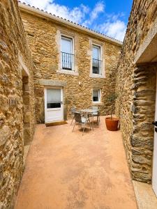 a patio with a table and chairs in a stone building at Do Bico Rooms in Camariñas