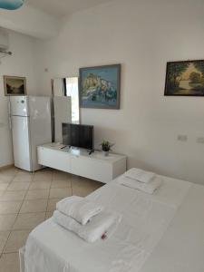 a white room with a bed and a refrigerator at Monda Apartments Dhermi in Dhërmi