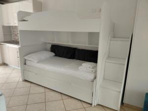 a white bunk bed in a kitchen with white shelves at Monda Apartments Dhermi in Dhërmi