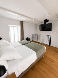 a bedroom with a large bed and a flat screen tv at Do Bico Rooms in Camariñas