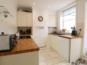 a kitchen with white cabinets and a clock on the wall at Springfield in Fakenham