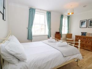 a bedroom with a white bed with blue curtains at Springfield in Fakenham