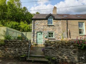 a stone house with a green door and a stone wall at Old Chapel House in Llanfairfechan