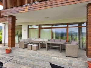 a patio with a couch and tables and windows at Къща за гости Торлашка среща in Vŭrbovo