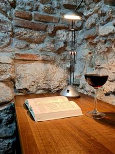 a book and a glass of wine on a table at La Tavernetta in Casto