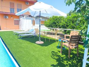 a patio with an umbrella and chairs next to a pool at Light Blue Room in Scordia