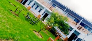 a building with a green yard with benches in front of it at MATENI's B&B in Naivasha