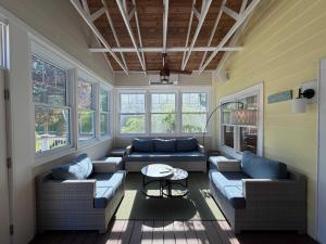 a living room with couches and a table and windows at Rise n Shine in Saugatuck