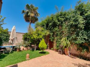 a garden with a palm tree and a umbrella at Darna in Marrakesh