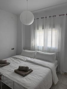 a white bedroom with a large bed with a towel on it at Casa Mirador in Loja