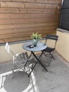 a patio table with two chairs and a vase of flowers at Le Jaurès in Brie-Comte-Robert
