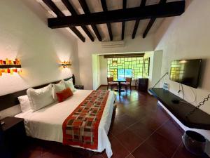 a bedroom with a bed and a table and a television at Hotel Hacienda Taboada (Aguas Termales) in San Miguel de Allende