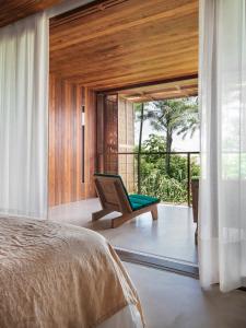 a bedroom with a bed and a chair on a balcony at Barracuda Hotel & Villas in Itacaré +70 photos