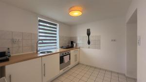 a kitchen with white cabinets and a sink and a window at Agnieszkas Pension in Havelberg