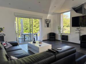 a living room with a black leather couch and a table at Maison charmante en bordure de la Creuse in Glénic