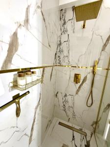 a bathroom with white marble walls and gold fixtures at Louise Luxury - free parking in Nyíregyháza +23 photos