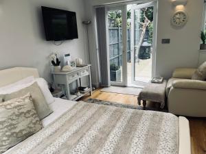 a living room with a couch and a tv at Garden Lodge, boutique - Walton on Thames in Walton-on-Thames
