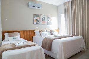 a bedroom with two beds with white sheets and a window at Hotel e Pousada VIVÁ in Chapada dos Guimarães +67 photos