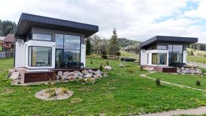 a small house with glass windows on a grass field at La Cuiburi in Sărişor