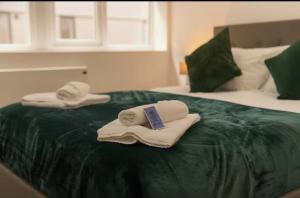 two towels sitting on top of a green bed at Comfortable 1 Bed Apartment Town Centre in Preston