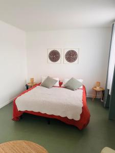a bedroom with a red and white bed with two pillows at Studio Les écuries de la forêt in Le Buisson Genois