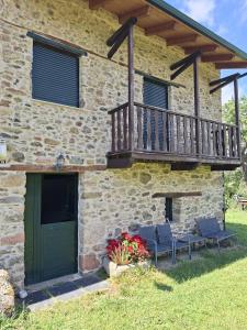a stone house with a balcony and two chairs at Apartamento en Casa Celia in Orol